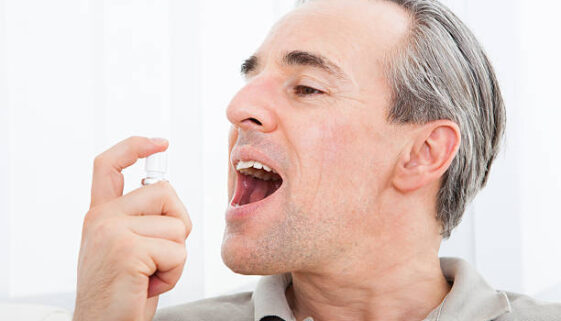 Close-up of a man applying Fresh breath spray